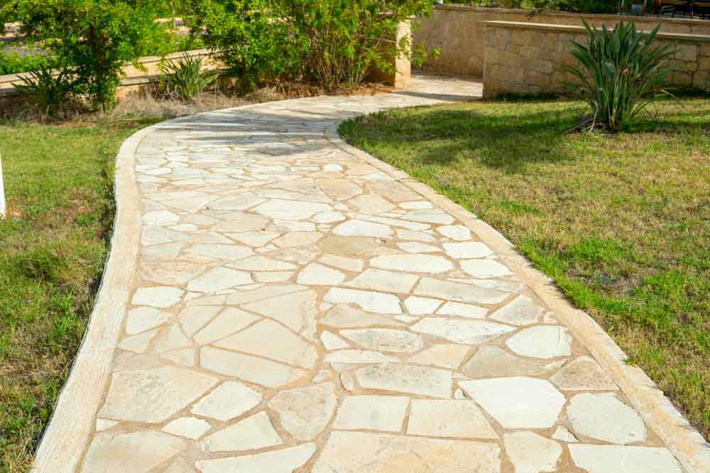 An intricately designed decorative concrete stone pathway winds gracefully through the landscape