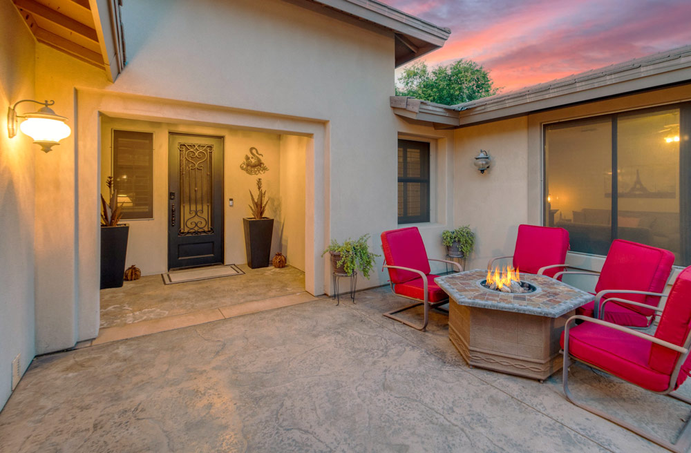 A stamped concrete patio for outdoor comfort and, on one corner, situated a welcoming table fire pit encircled by a collection of chairs