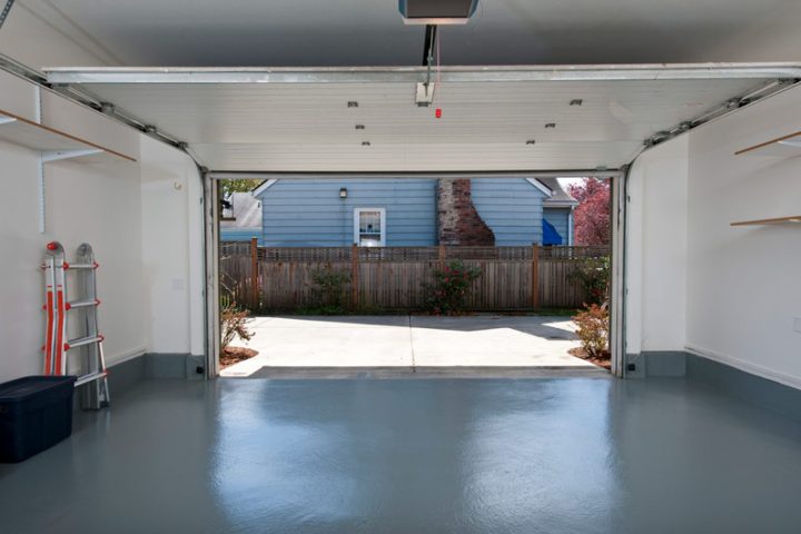 A residential garage floor, coated with a protective layer of glossy acrylic sealant, radiates a smooth and lustrous finish, transforming the space into a clean and attractive area