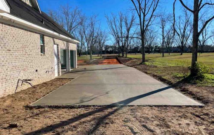 Wet Concrete on a driveway leading to a brick house
