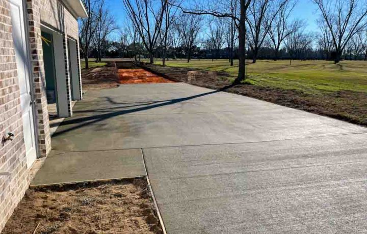 Wet Concrete on a driveway leading to the garage of a brick house