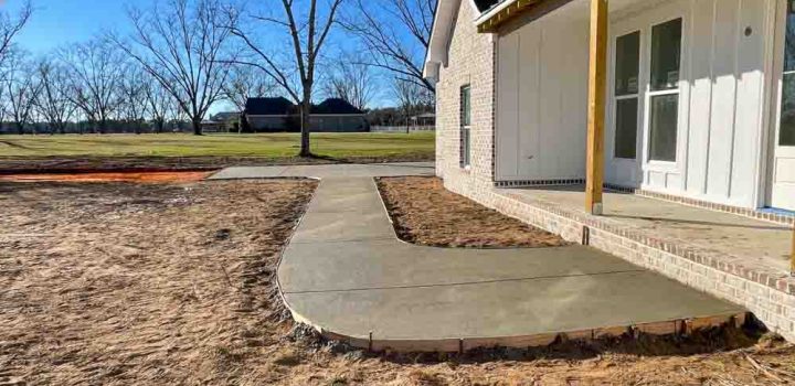 Wet concrete on a sidewalk leading to the front porch of a brick house